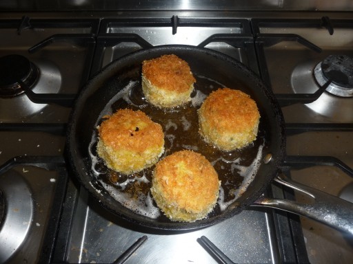 scotch eggs cooking in a frying pan