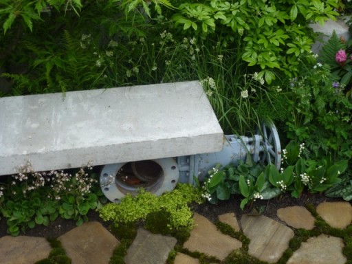 an old pipe supports a garden bench