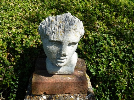 mans head on a pedestal in charleston garden