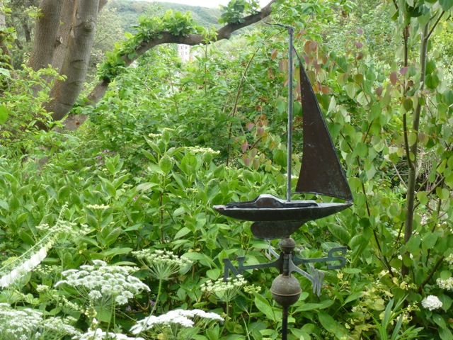 copper weathervane off ship placed among plants in the garden