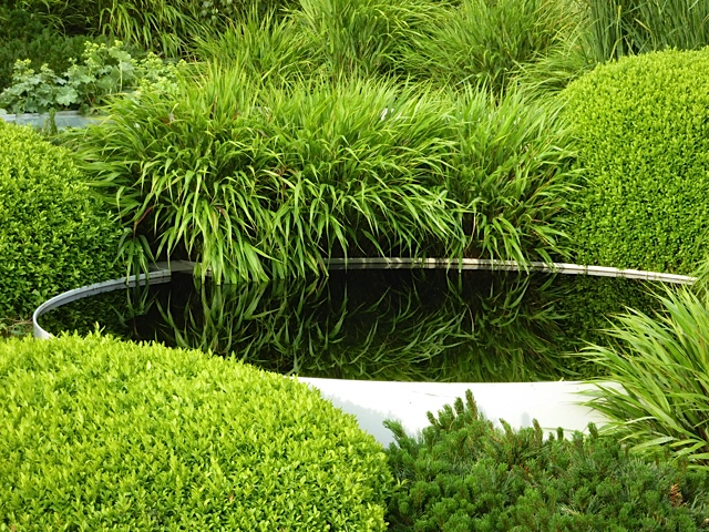 water feature surrounded by lush grass and buxus