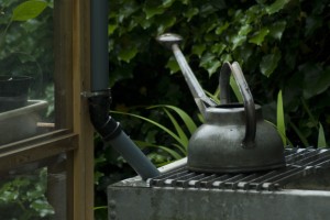 old watering can standing on rain tank