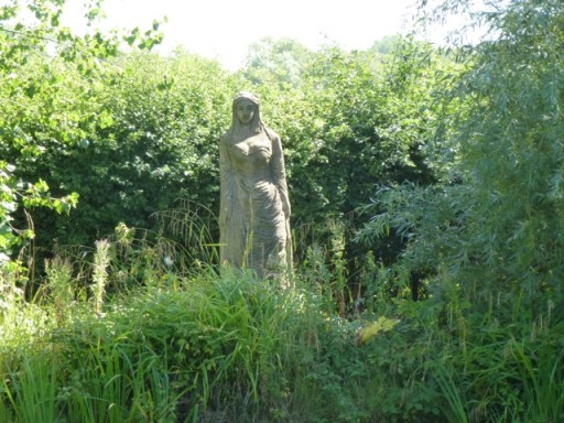 woman carved from stone amongst grasses at charleston
